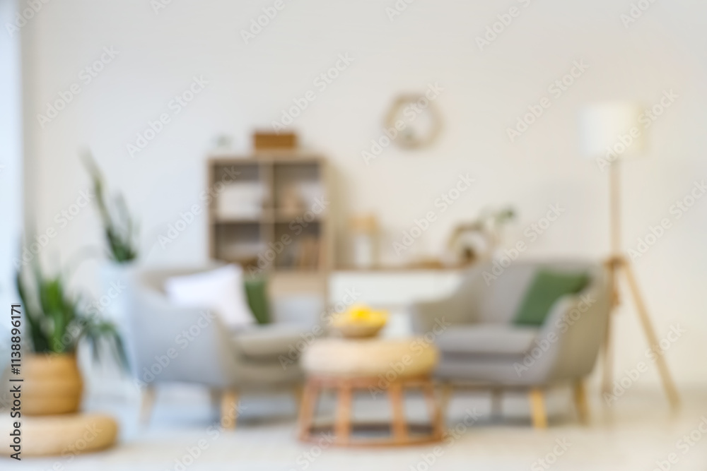 Obraz premium Blurred view of light living room with grey armchairs, table and shelf unit