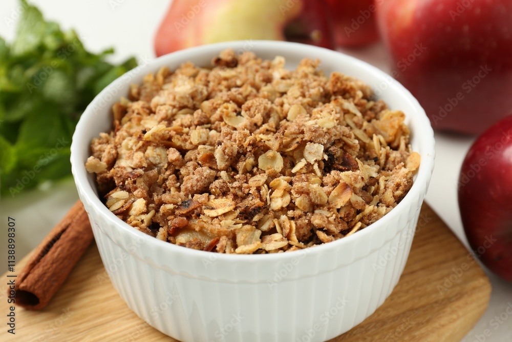 Delicious apple crisp in bowl, cinnamon, fresh fruits and mint on table, closeup Delicious apple crisp in bowl, cinnamon, fresh fruits and mint on table, closeup