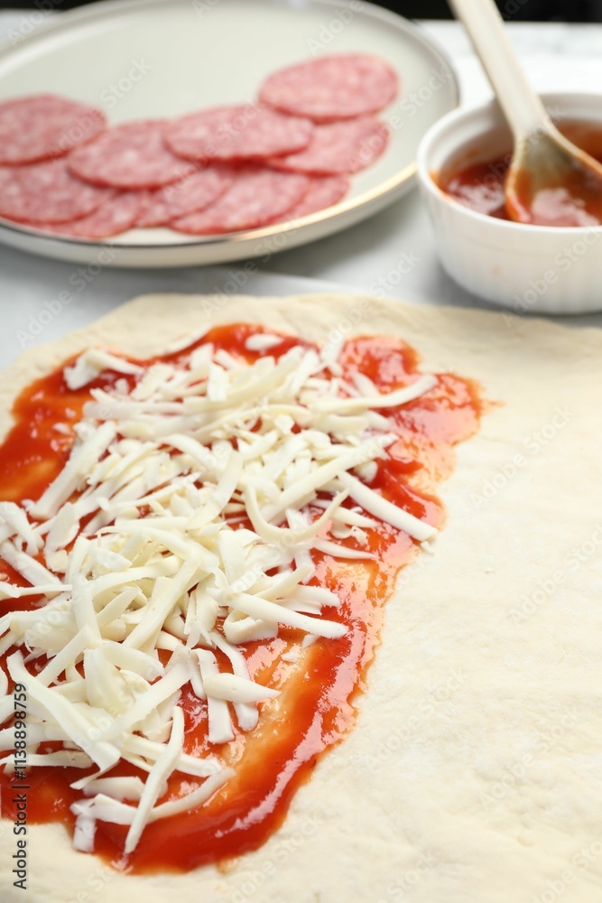 Making calzone pizza. Dough with sauce, cheese and other ingredients on table, closeup Making calzone pizza. Dough with sauce, cheese and other ingredients on table, closeup