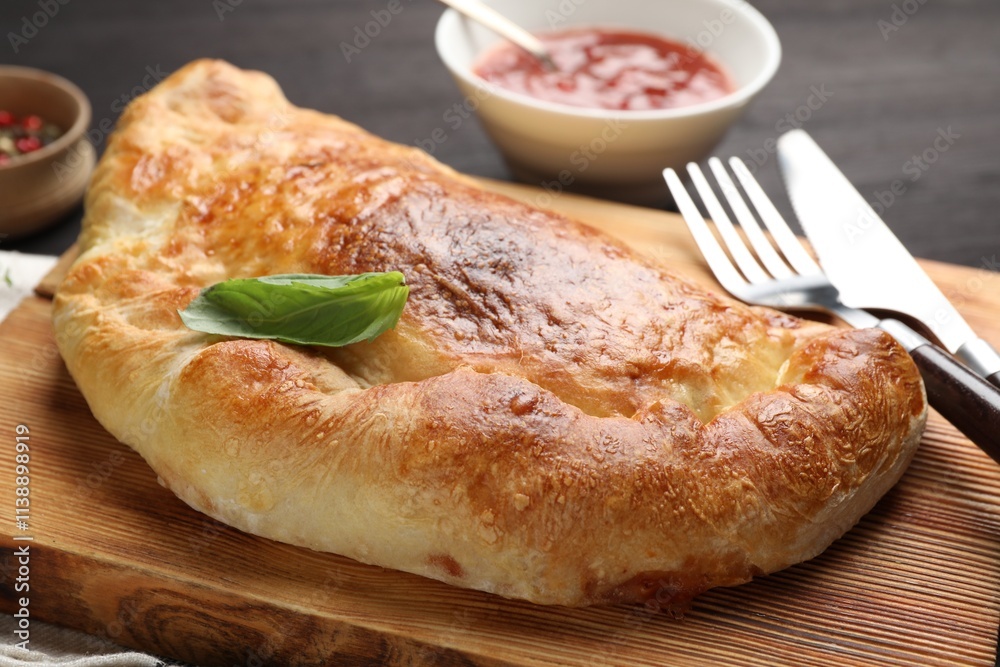 Delicious fresh calzone pizza served on wooden table, closeup Delicious fresh calzone pizza served on wooden table, closeup