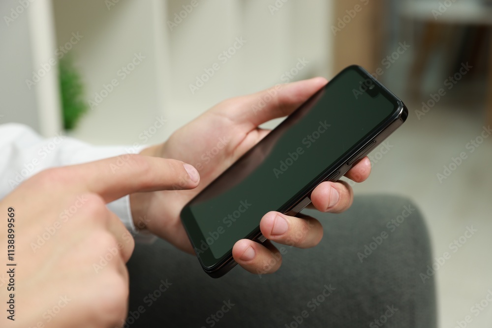 Man using smartphone with blank screen indoors, closeup Man using smartphone with blank screen indoors, closeup