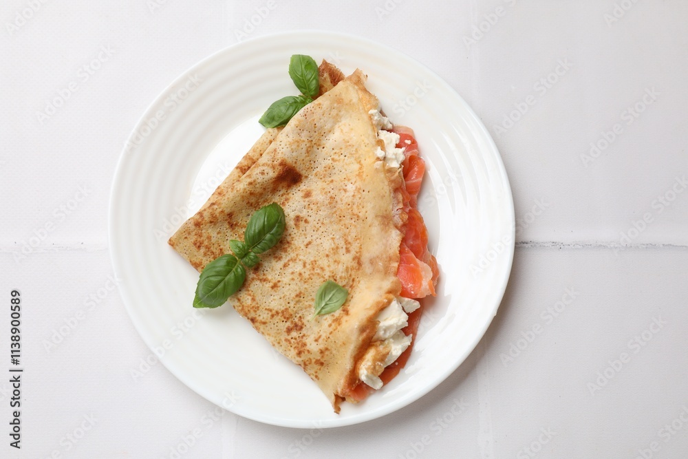Delicious crepe with salmon, cream cheese and basil on white tiled table, top view Delicious crepe with salmon, cream cheese and basil on white tiled table, top view