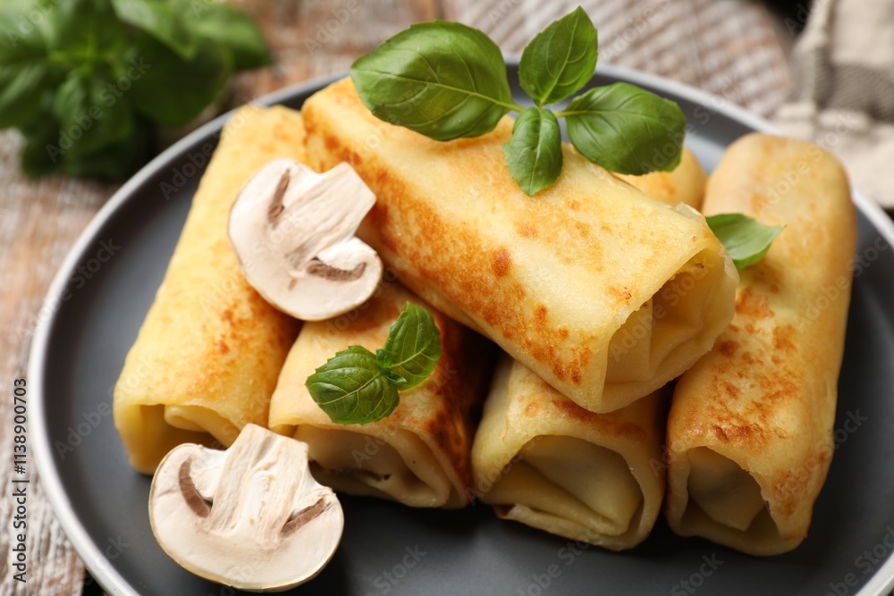 Delicious rolled crepes with mushrooms and basil on table, closeup Delicious rolled crepes with mushrooms and basil on table, closeup