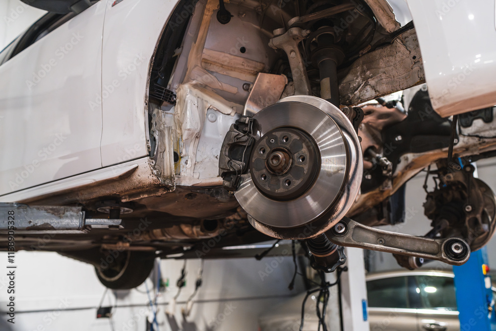 Car disk brake getting fixed on elevated vehicle in auto repair shop Car disk brake getting fixed on elevated vehicle in auto repair shop