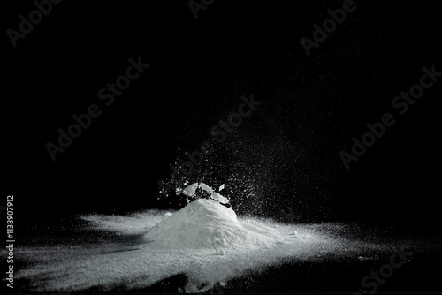 Baking soda powder explode in mid air. Powder of baking soda flying like explosion splashing, prepare to clean food vegetable as sodium bicarbonate carbonate, black background isolated photo