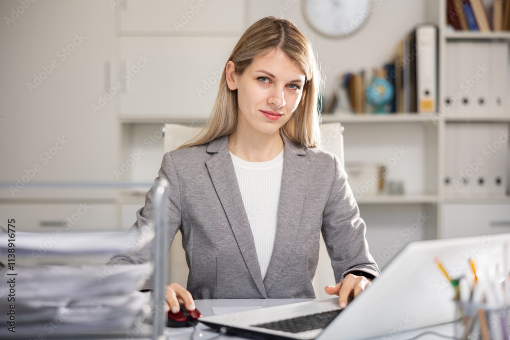 Young woman bookkeeper working in her workplace in office and looking at camera. Young woman bookkeeper working in her workplace in office and looking at camera.