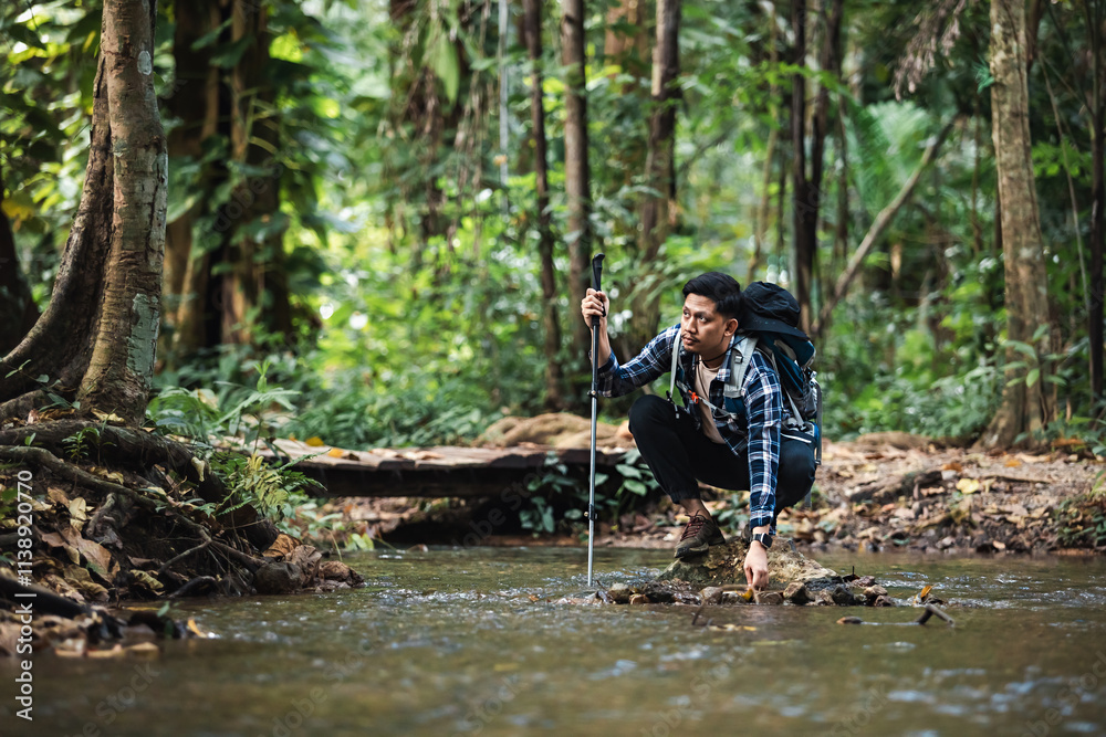 Asian hiker man with backpack sitting and touching fresh water in the forest. Asian hiker man with backpack sitting and touching fresh water in the forest.