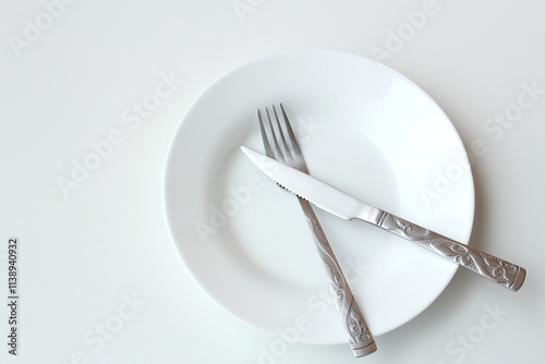 Photos Empty plate with crossed cutlery symbolizing lack of food or malnutrition concept