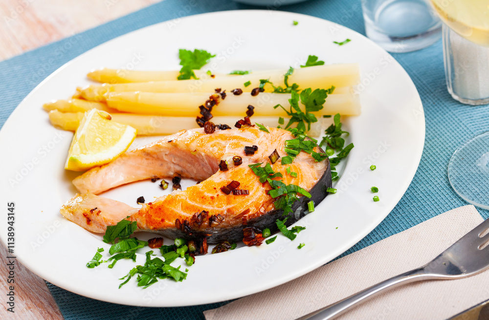 Traditional spanish food, grilled salmon with asparagus served with lemon and greens Traditional spanish food, grilled salmon with asparagus served with lemon and greens