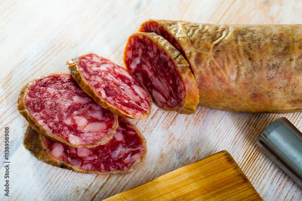 Spanish salchichon sausage cut in slices on a wooden surface, close-up Spanish salchichon sausage cut in slices on a wooden surface, close-up