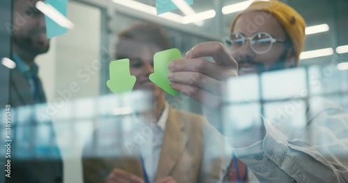 Team of professionals place sticky notes on glass wall