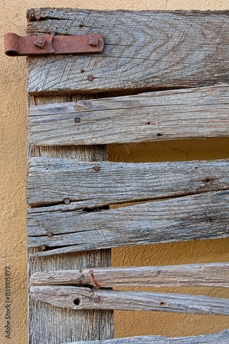 Corner.of wooden horizontal slat gate with rusty hardware