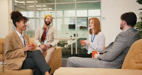 Diverse team enjoys coffee break in office building rest area