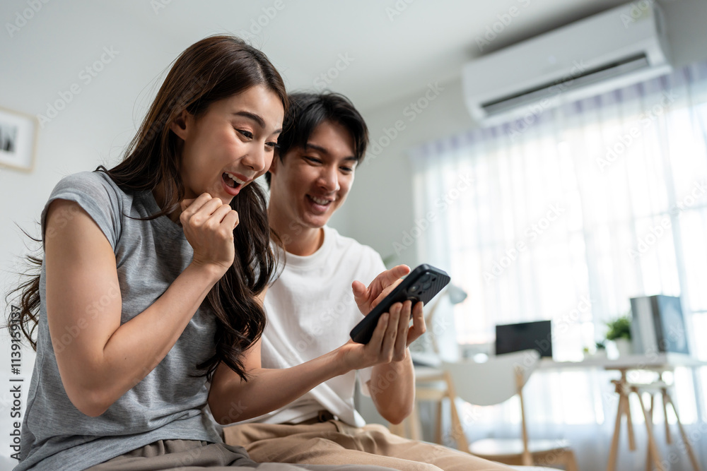 Fototapeta premium Asian young couple using smartphone shopping online in bedroom at home.