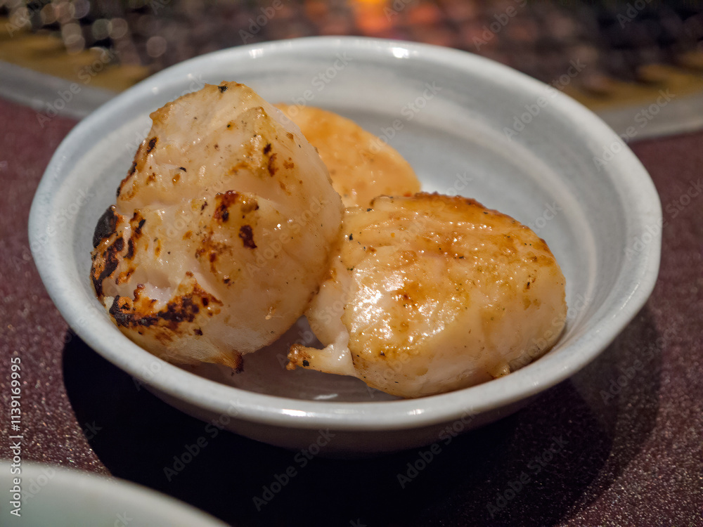 Fototapeta premium Three grilled scallops in ceramic bowl close-up