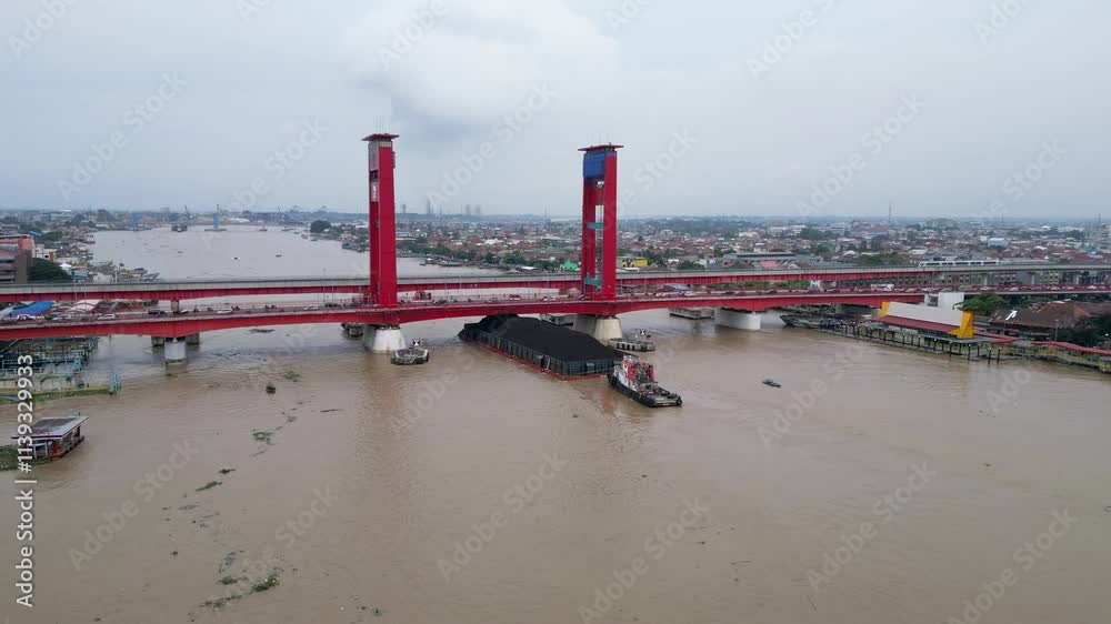 Barges carrying coal pass the Ampera Bridge on the Musi River Barges carrying coal pass the Ampera Bridge on the Musi River