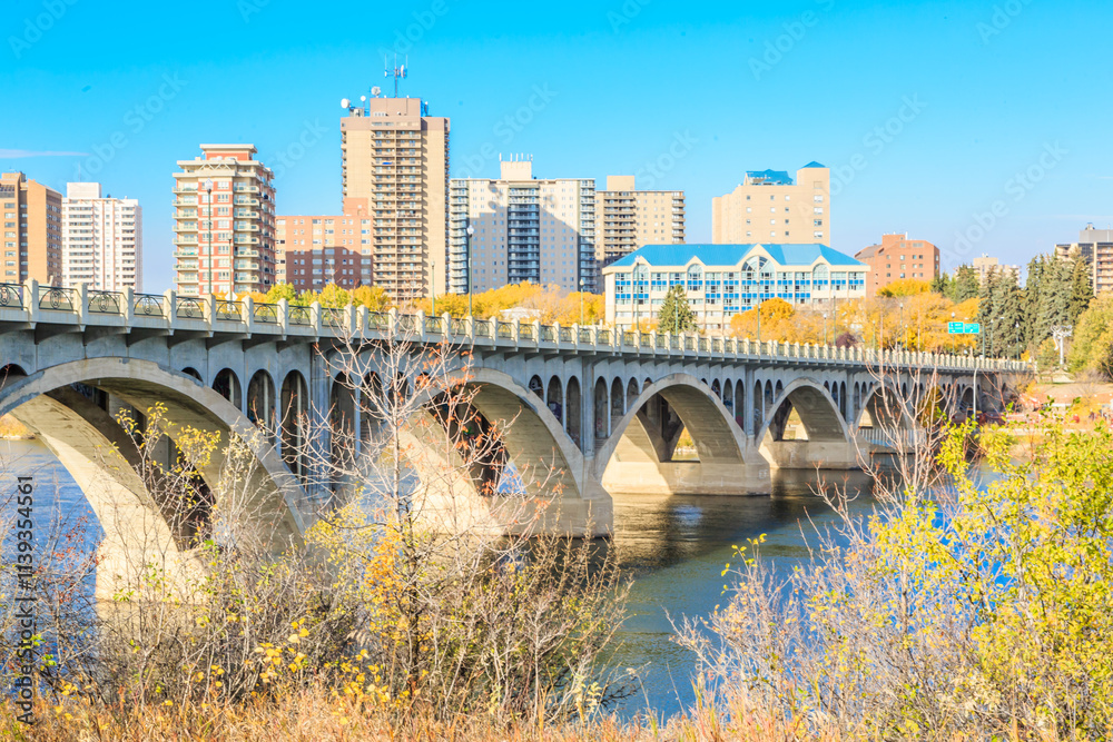 Naklejka premium A bridge spans a river in a city with tall buildings in the background