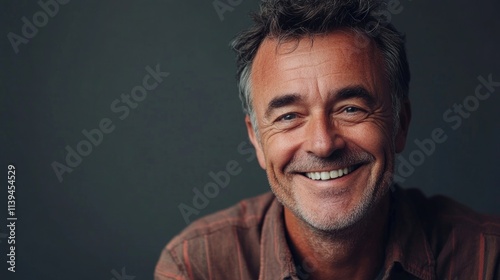 Mature man with a happy expression, smiling on a gray background