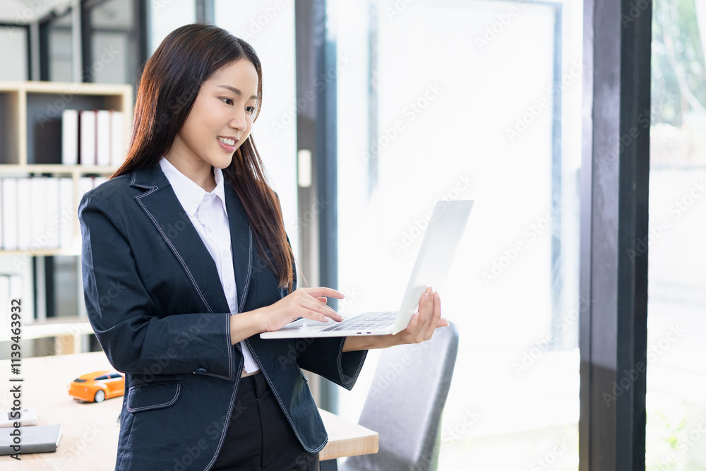 Asian businesswoman working on digital laptop standing in office, Businesswoman and Marketing concept. Asian businesswoman working on digital laptop standing in office, Businesswoman and Marketing concept.
