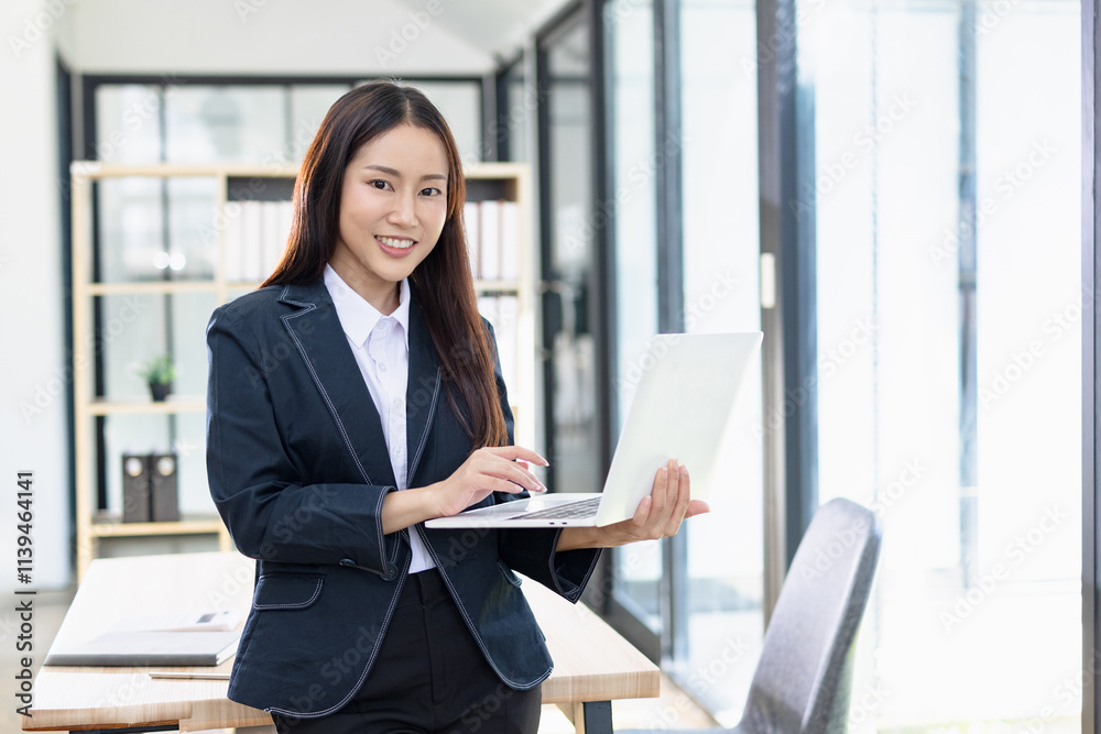 Asian businesswoman working on digital laptop standing in office, Businesswoman and Marketing concept. Asian businesswoman working on digital laptop standing in office, Businesswoman and Marketing concept.
