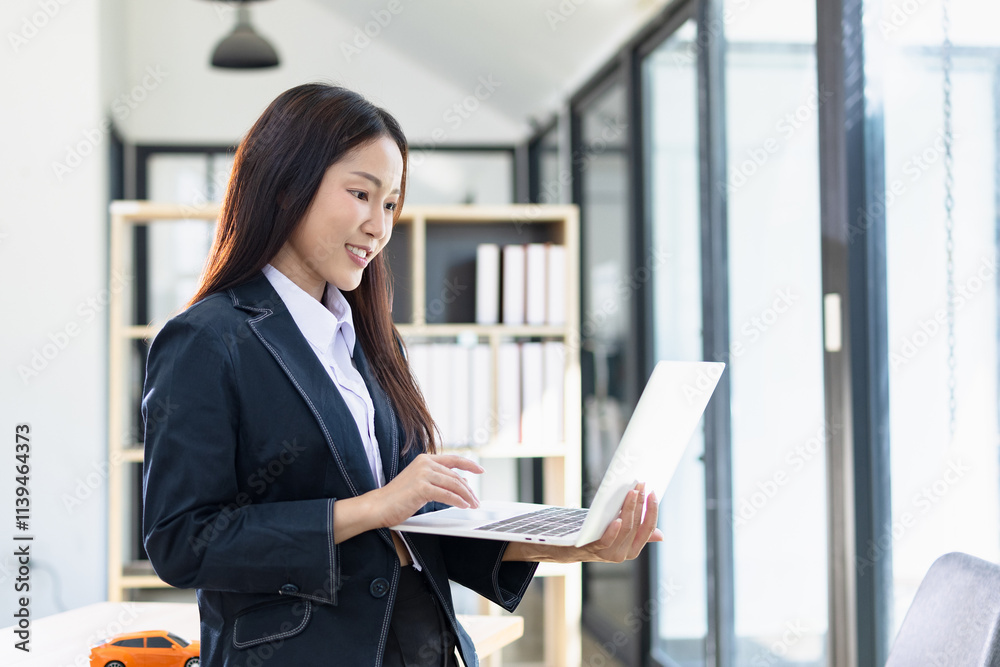 Asian businesswoman working on digital laptop standing in office, Businesswoman and Marketing concept. Asian businesswoman working on digital laptop standing in office, Businesswoman and Marketing concept.