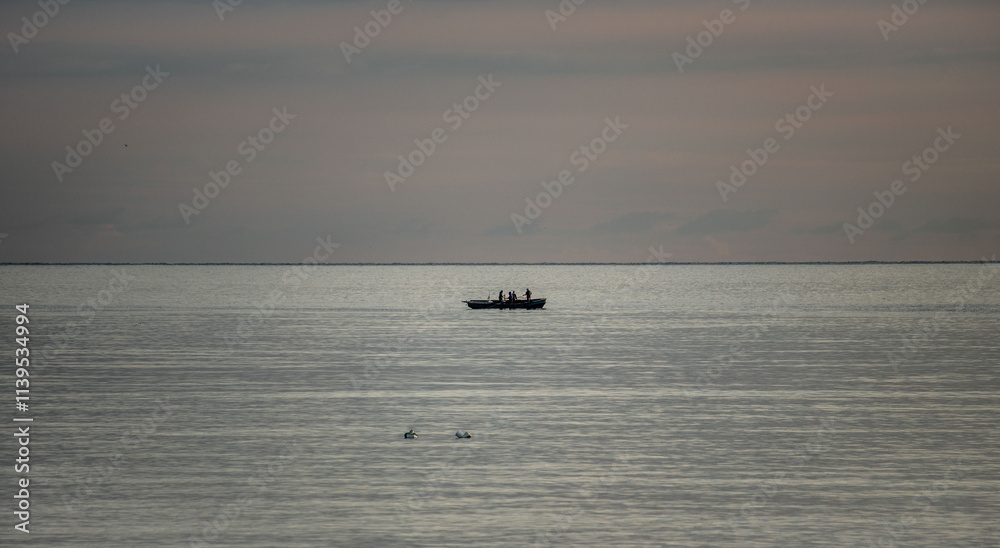 A boat is floating in the ocean with a few people on board A boat is floating in the ocean with a few people on board
