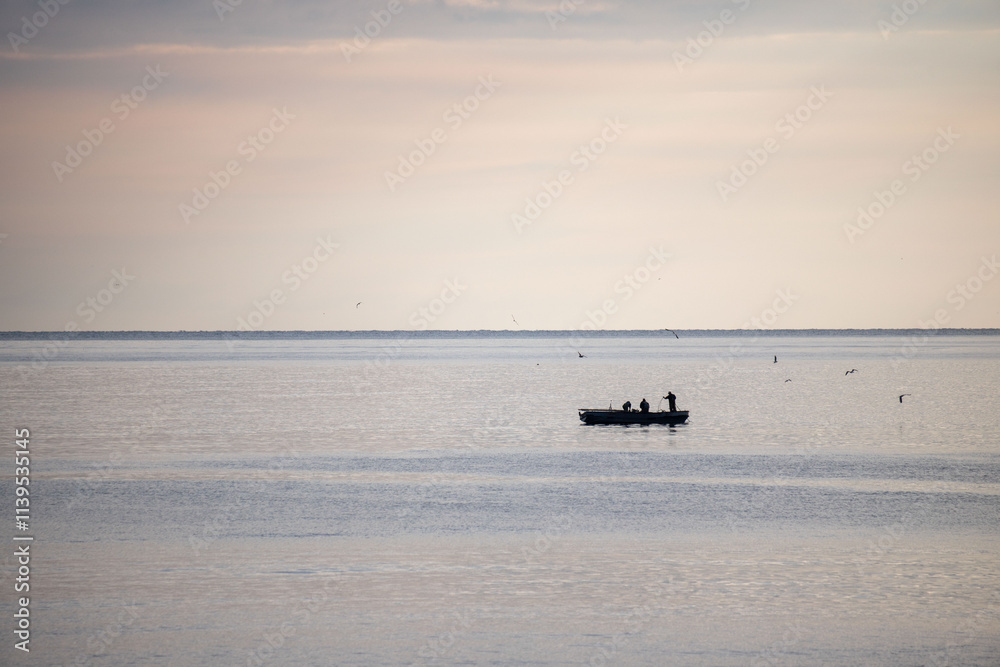 A boat is floating on the water with a man in it A boat is floating on the water with a man in it