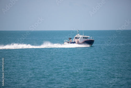 A boat is traveling through the ocean with a blue sky in the background