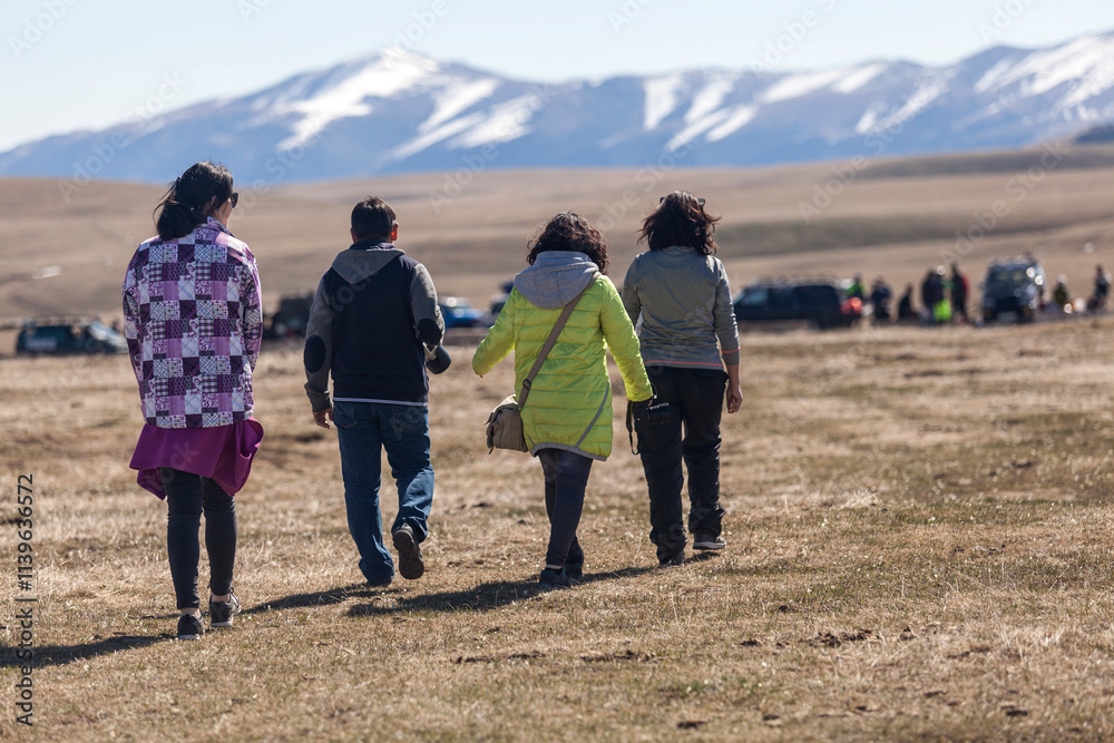 Group walking in a field with snowy mountains in the background. Group walking in a field with snowy mountains in the background.