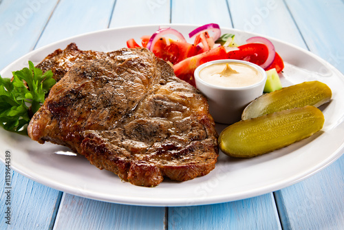 Roasted chuck steak with mayonnaise and fresh vegetables on wooden table