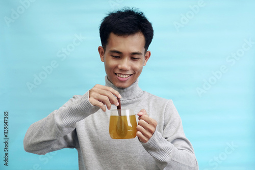 Young Asian man busy stirring herbal tea with wooden spoon