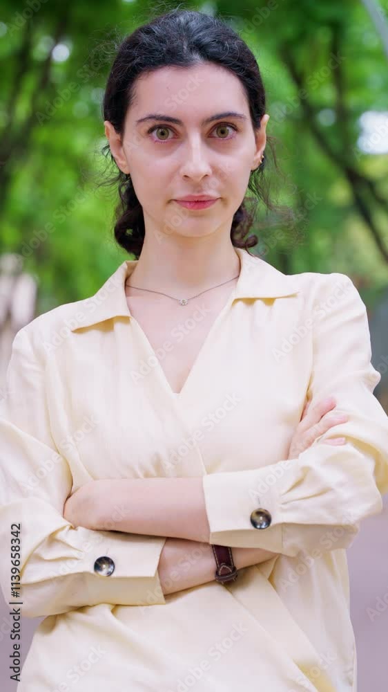 Confident young woman standing with arms crossed outdoors.Vertical Confident young woman standing with arms crossed outdoors.Vertical