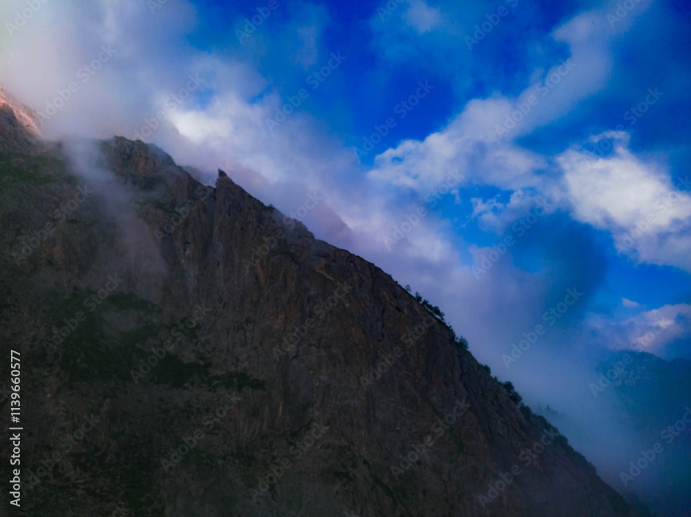 the top of a mountain with the sun coming down and clouds coming through the air the top of a mountain with the sun coming down and clouds coming through the air