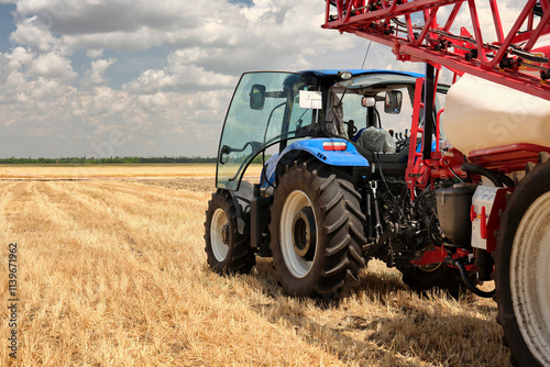 Rear view of  tractor with trailer agricultural equipment for spraying fertilizers or water on the fields. Start tillage after harvest.