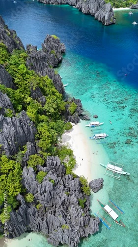 Pristine Beach with Boats Along Limestone Cliffs in a Tropical Paradise photo