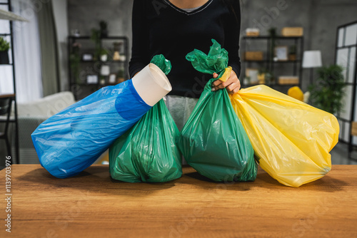 Person organizing colorful recycling bags in modern living room photo