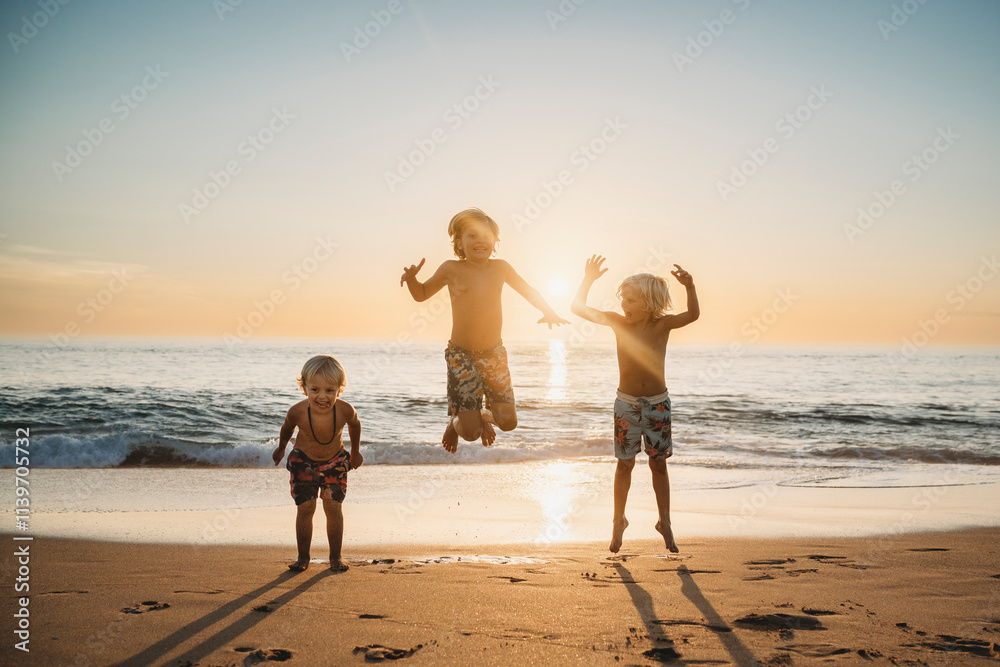 Young brothers jumping at beach having fun during summer sunset Young brothers jumping at beach having fun during summer sunset