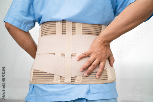 Asian lady patient wearing back pain support belt for orthopedic lumbar with walker.