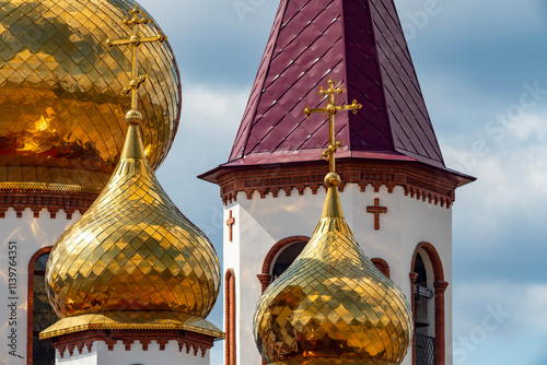 Golden dome of the church with a golden cross against the background of a cloudy sky.