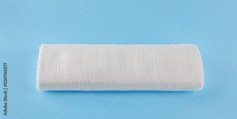 Fototapeta premium Gauze medical bandage on a blue background. Roll of bandage.