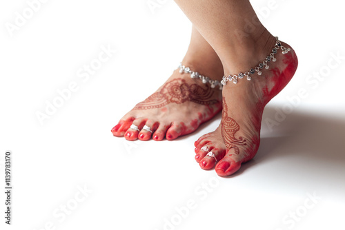 Indian Wedding Concept. Beautiful feet of an Indian bride, decorated with auspicious Mehndi, anklets, red dye (aalta) and toe rings.