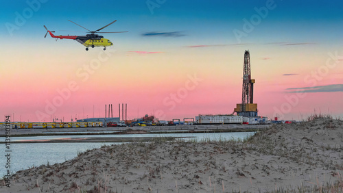 Oil and gas field in the Arctic. Summer. Sandy landscape with small lakes. Drilling rig. Flying helicopter