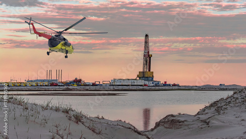 Oil and gas field in the Arctic. Summer. Sandy landscape with small lakes. Drilling rig. Flying helicopter.