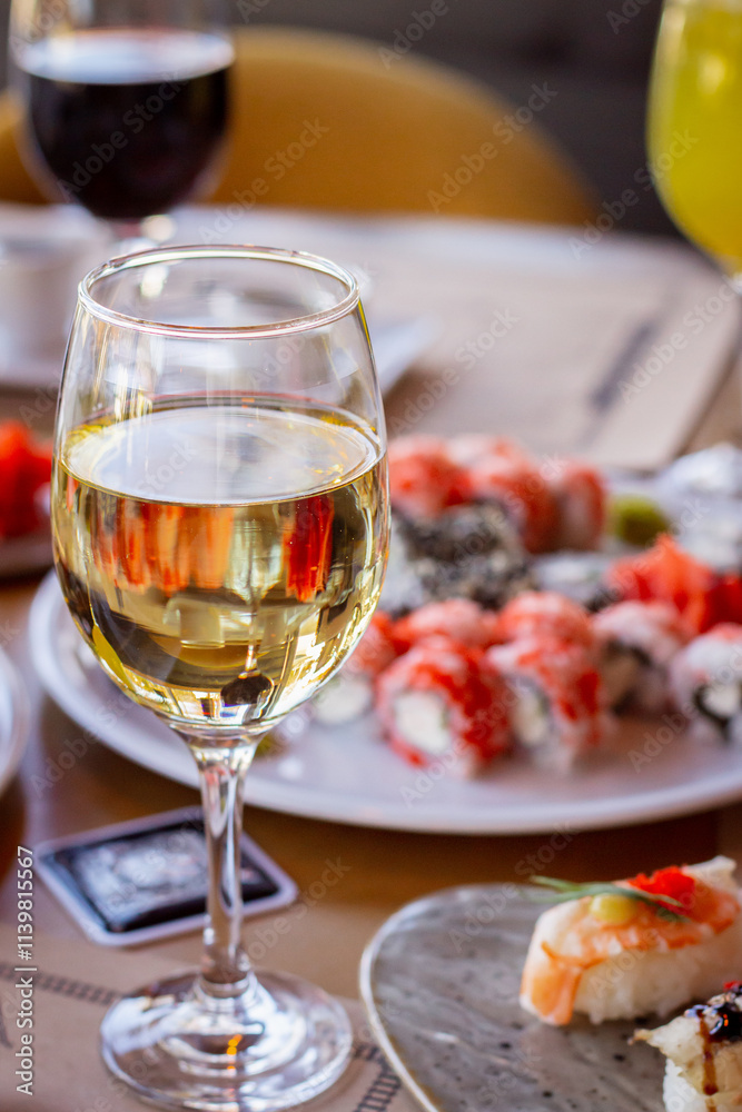 Glass of White Wine Against a Set Table with Sushi Glass of White Wine Against a Set Table with Sushi