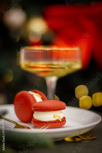 Two Red Macarons with a Champagne Glass and Christmas Tree Lights in the Background