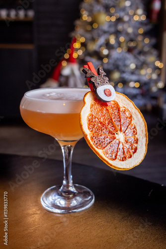 Сocktail garnish with dried grapefruit and reindeer hairpin, blurred Christmas tree lighOrange Cocktail with Dried Grapefruit Garnish and a Reindeer Clothespin, Set Against a Blurred Bts on background