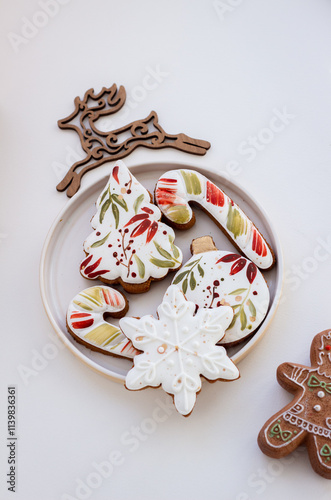 Cozy Christmas Photo with Hand-Painted Gingerbread Cookies on a Plate, Surrounded by Christmas Decor on a White Background