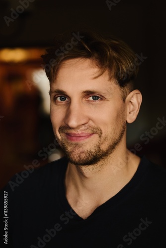 Close-up portrait of handsome young Caucasian man smiling against apartment background