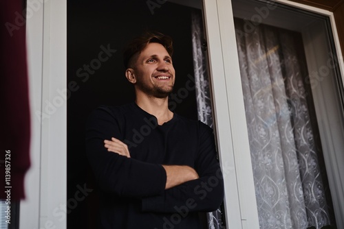 Close-up portrait of handsome young Caucasian man smiling against apartment background