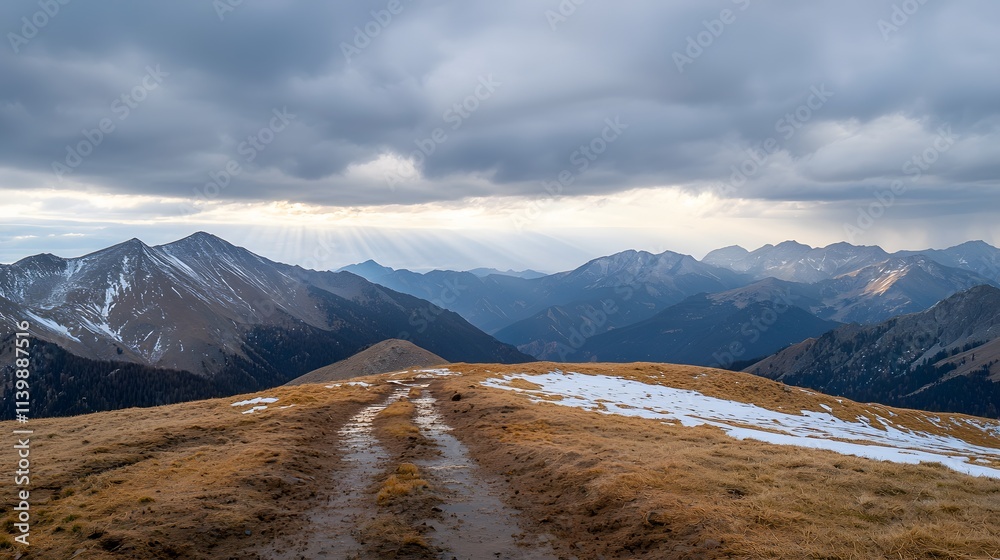 Fototapeta premium A Majestic View of a Vast Mountain Range Coated in Wet Snow Under Dramatic Cloudy Skies with Soft Light Streaming Through the Peaks